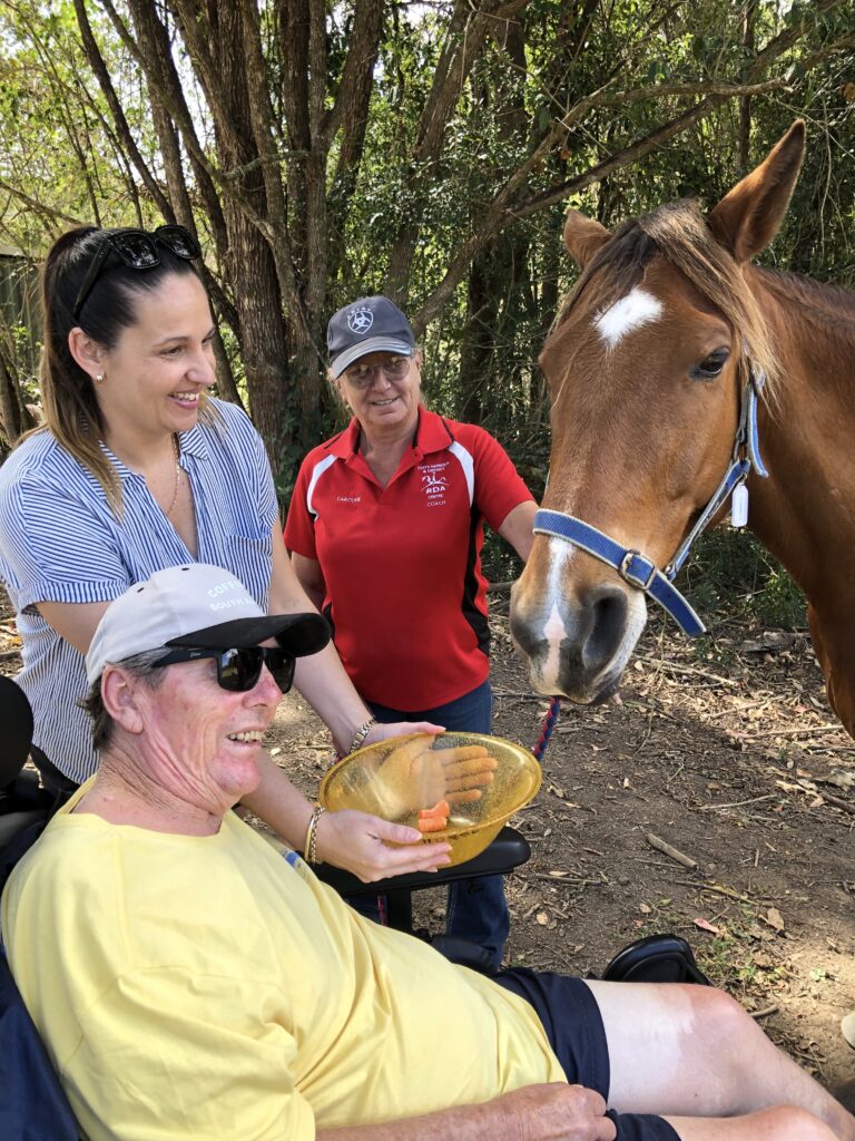Man using a wheelchair enjoying feeding a horse